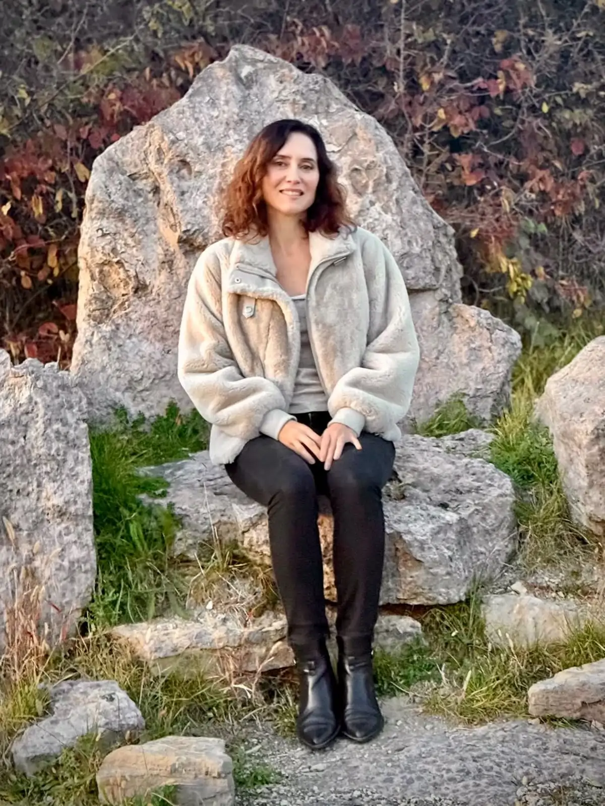 Isabel Díaz Ayuso sentada al aire libre en un entorno natural